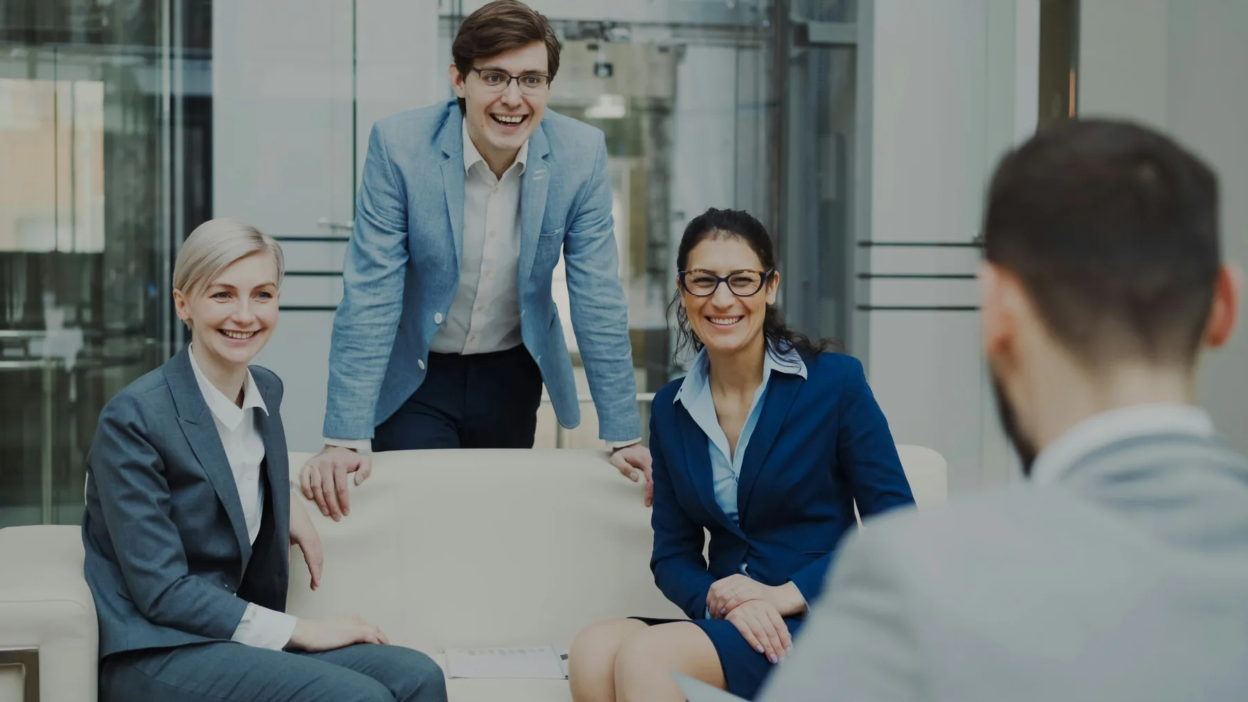 Professionnels souriants accueillant un client dans un espace de rencontre lumineux